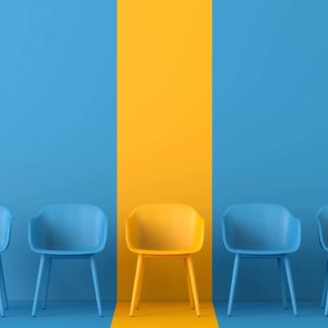 A row of five chairs against a wall showcases a striking design, with a wide vertical yellow stripe. The chairs are blue, except for the center one, which is yellow. The wall features alternating blue and yellow hues that match the chairs perfectly.