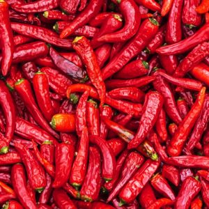 A vibrant pile of fresh red chili peppers, reminiscent of the dynamic world of digital marketing, fills the frame. The peppers vary in size and shape, with glossy skins and green stems, creating a rich, textured pattern that parallels innovative web development strategies.
