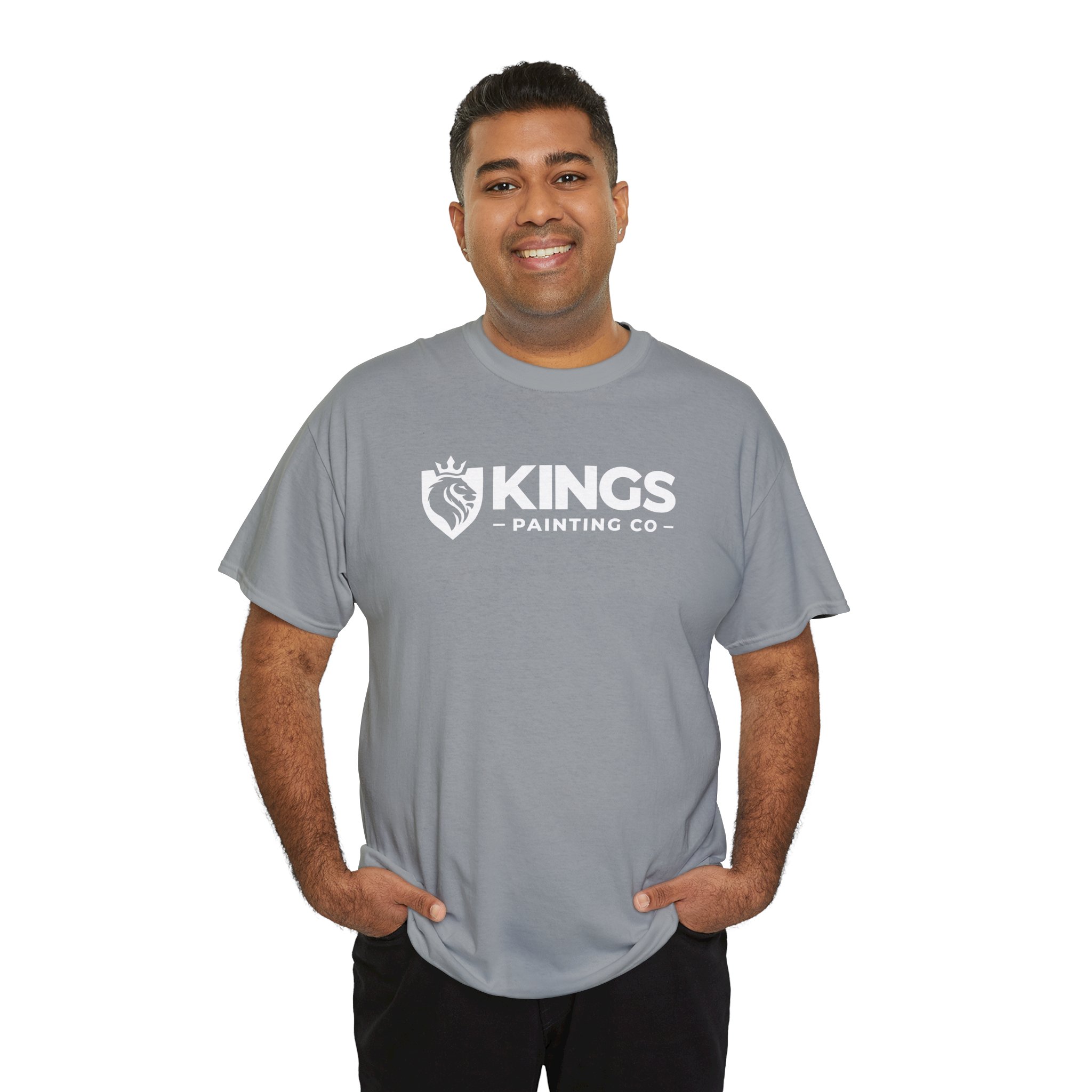 A smiling man stands against a white background with his hands in his pockets, wearing the Kings Painting Co. Logo T‑Shirt (Classic) in gray—featuring a lion and crown logo on a Gildan Ultra Cotton (G5000) tee.